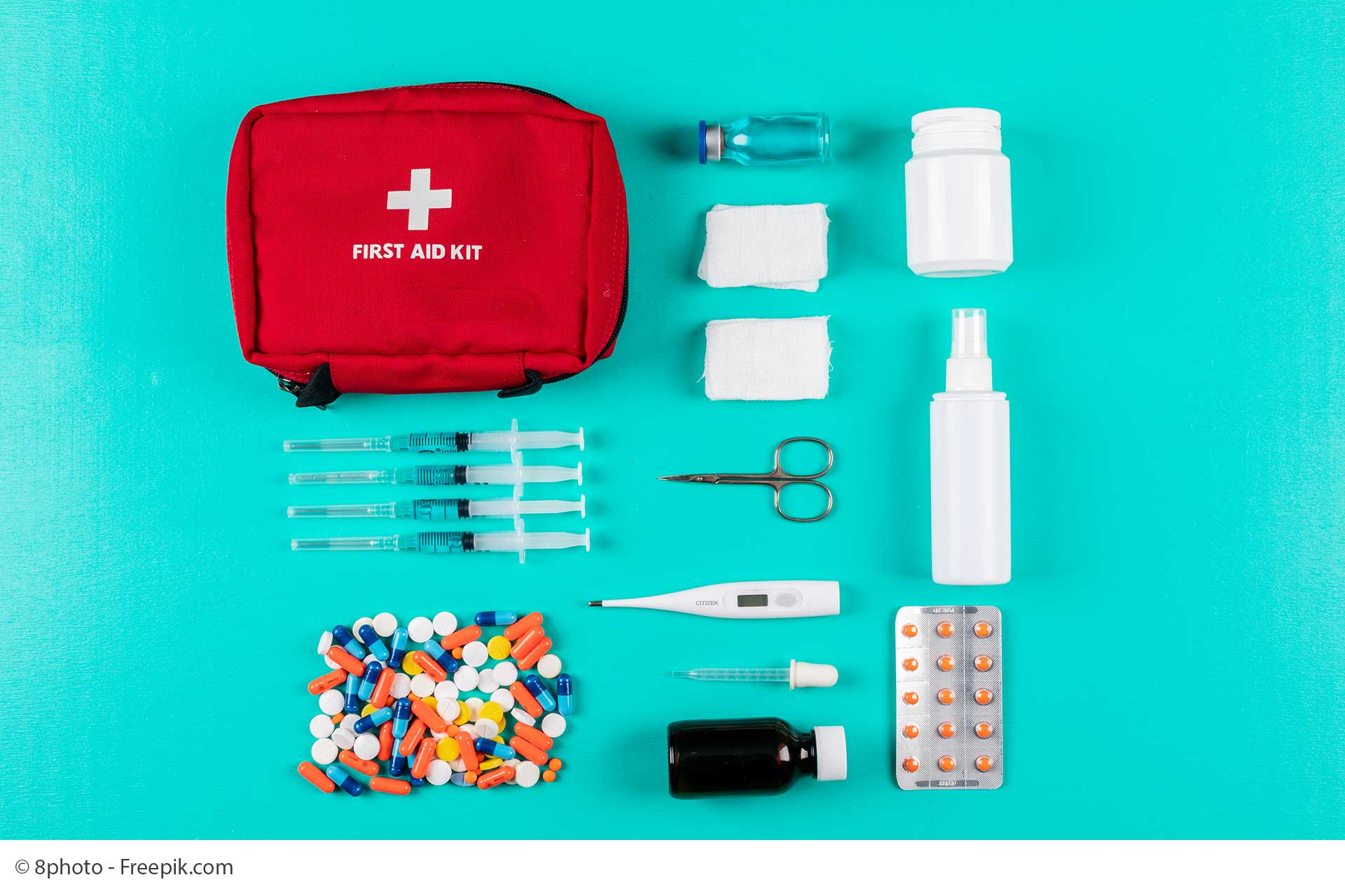 flat lay first aid kit with pills thermometer spray pills bandage cyan blue background horizontal WEB